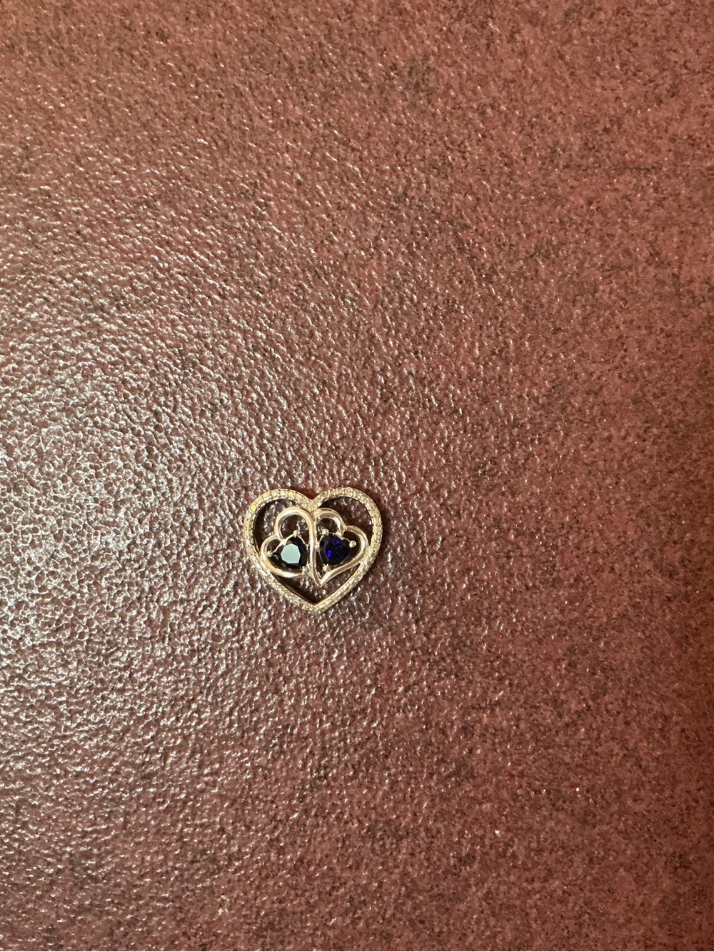 Silver heart necklace pendant with sapphire and diamond chip accents.